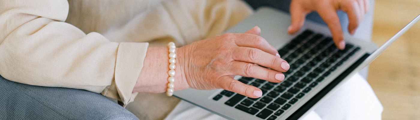 senior woman typing important report on keyboard of laptop